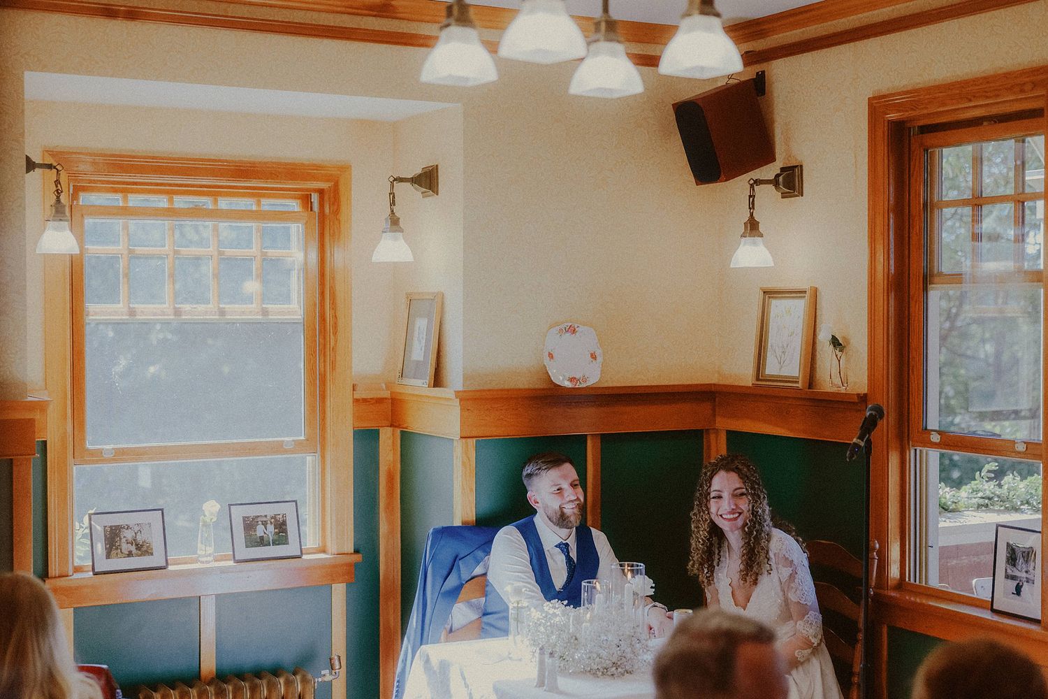 Interior of a wedding venue with wooden beams and white pendant lights creating a warm atmosphere.
