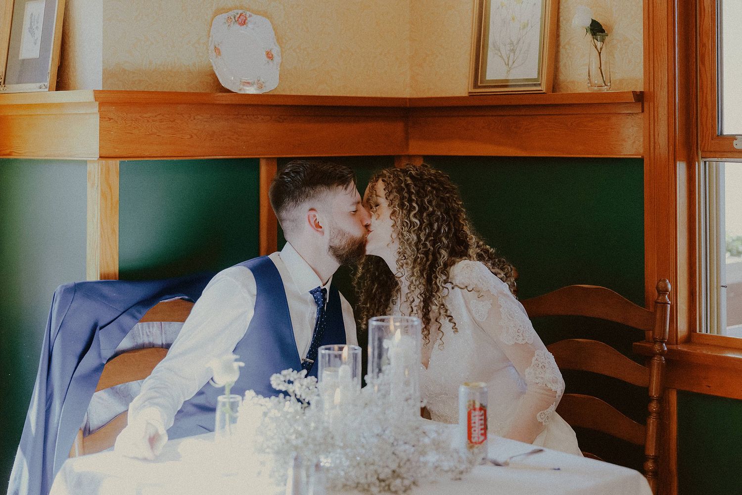 Wedding reception table settings with elegant floral centerpieces in a warm-lit wooden interior.