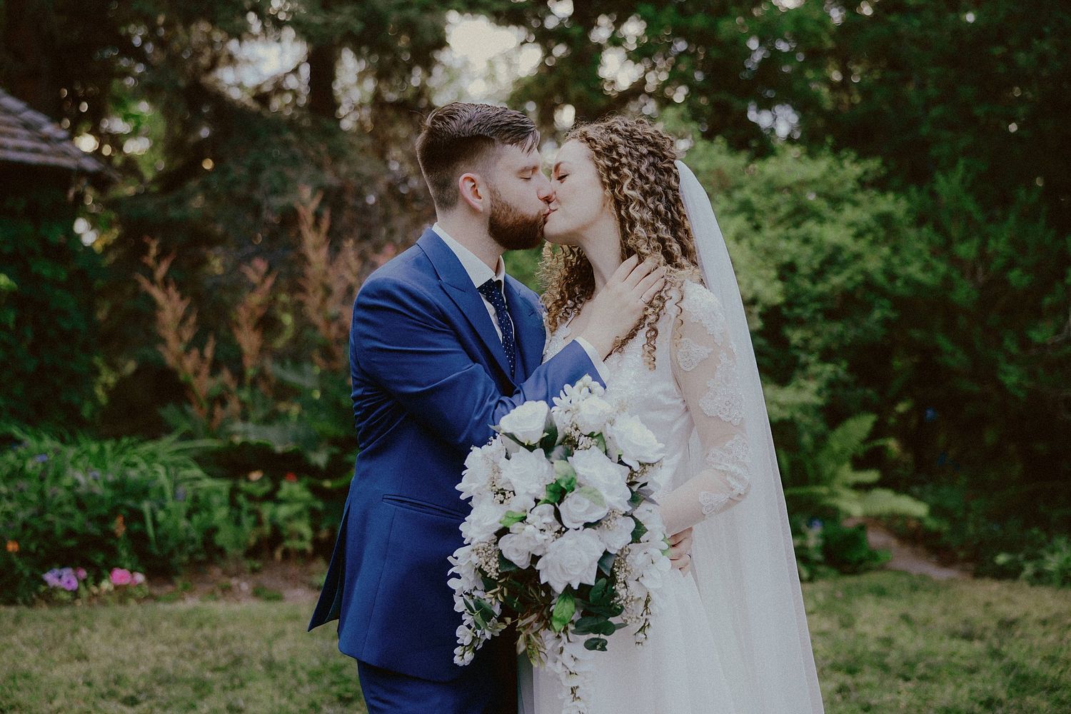 Romantic outdoor wedding portraits among lush green foliage.