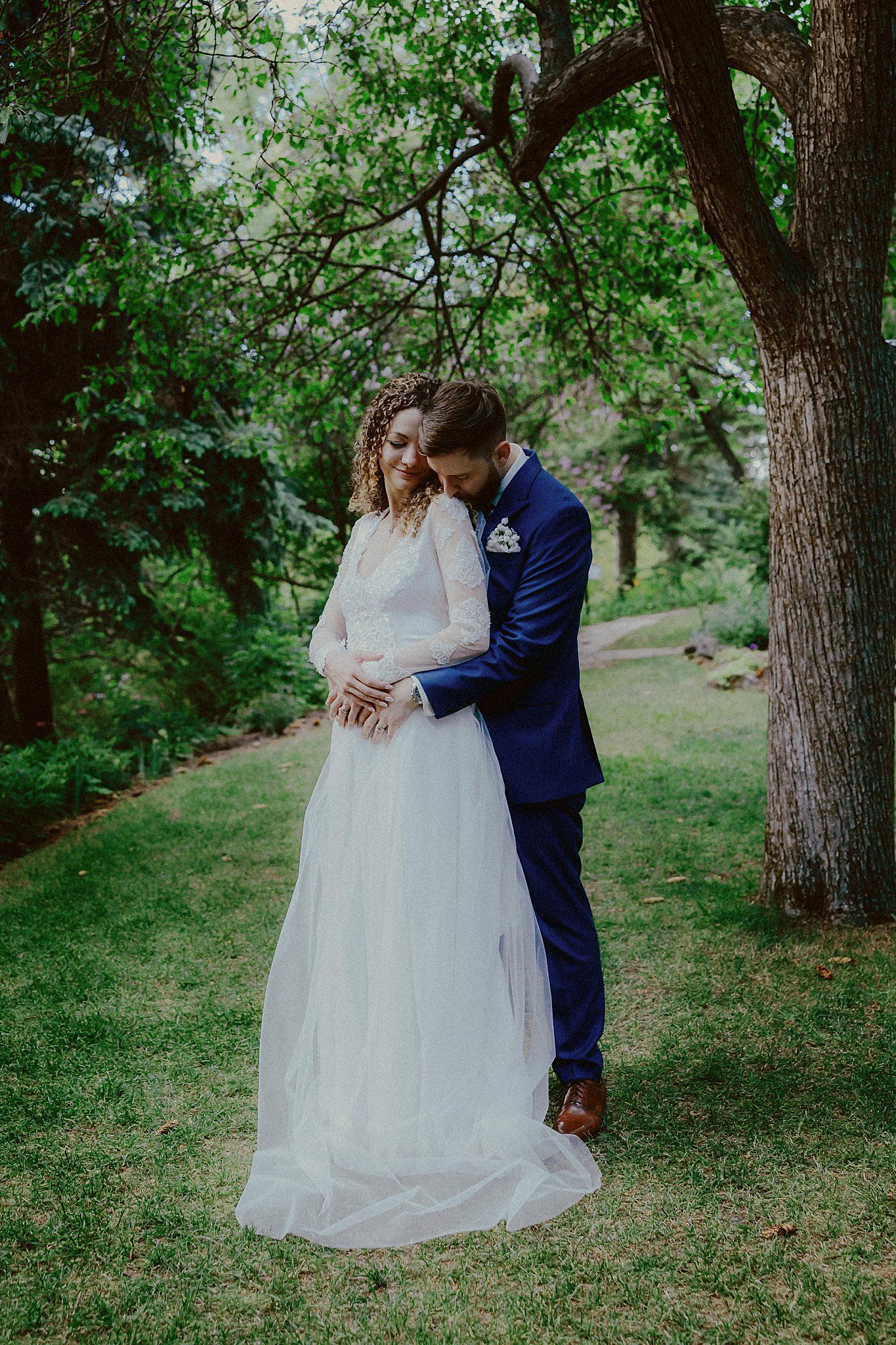 Romantic wedding portraits taken in a serene wooded setting with natural greenery.