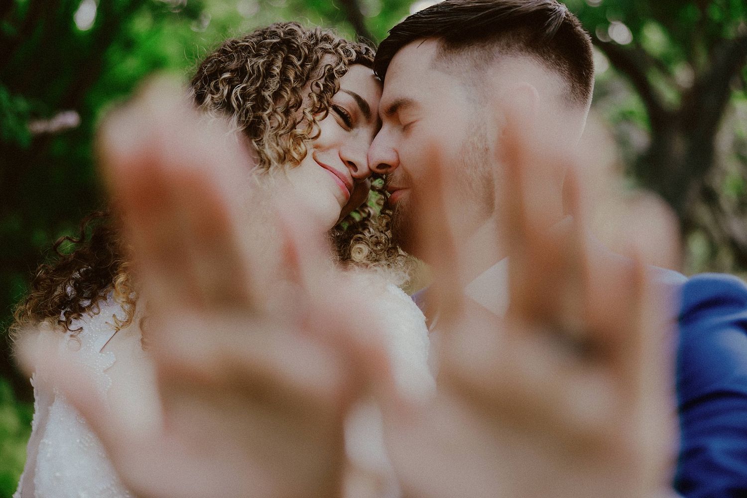 Close-up intimate moment between two people with curly hair outdoors.