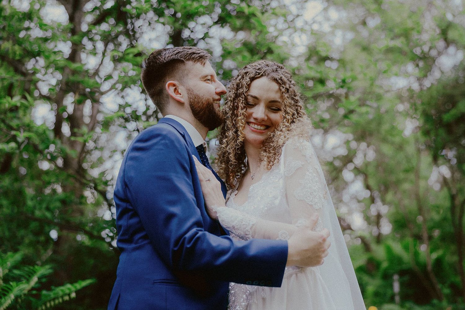 Romantic wedding couple sharing intimate moments in a garden setting with spring blossoms.