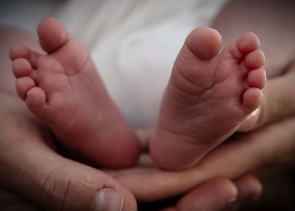 Close-up shots of tiny newborn baby feet and toes against a soft blurred background.