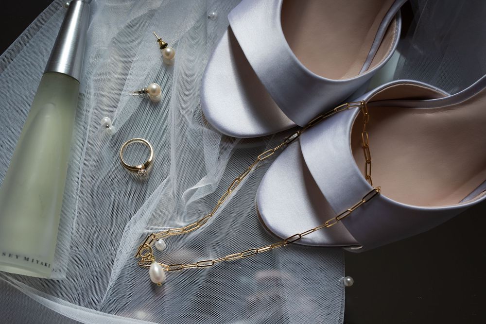 Wedding rings and delicate jewelry pieces arranged artistically on a light surface with soft shadows.