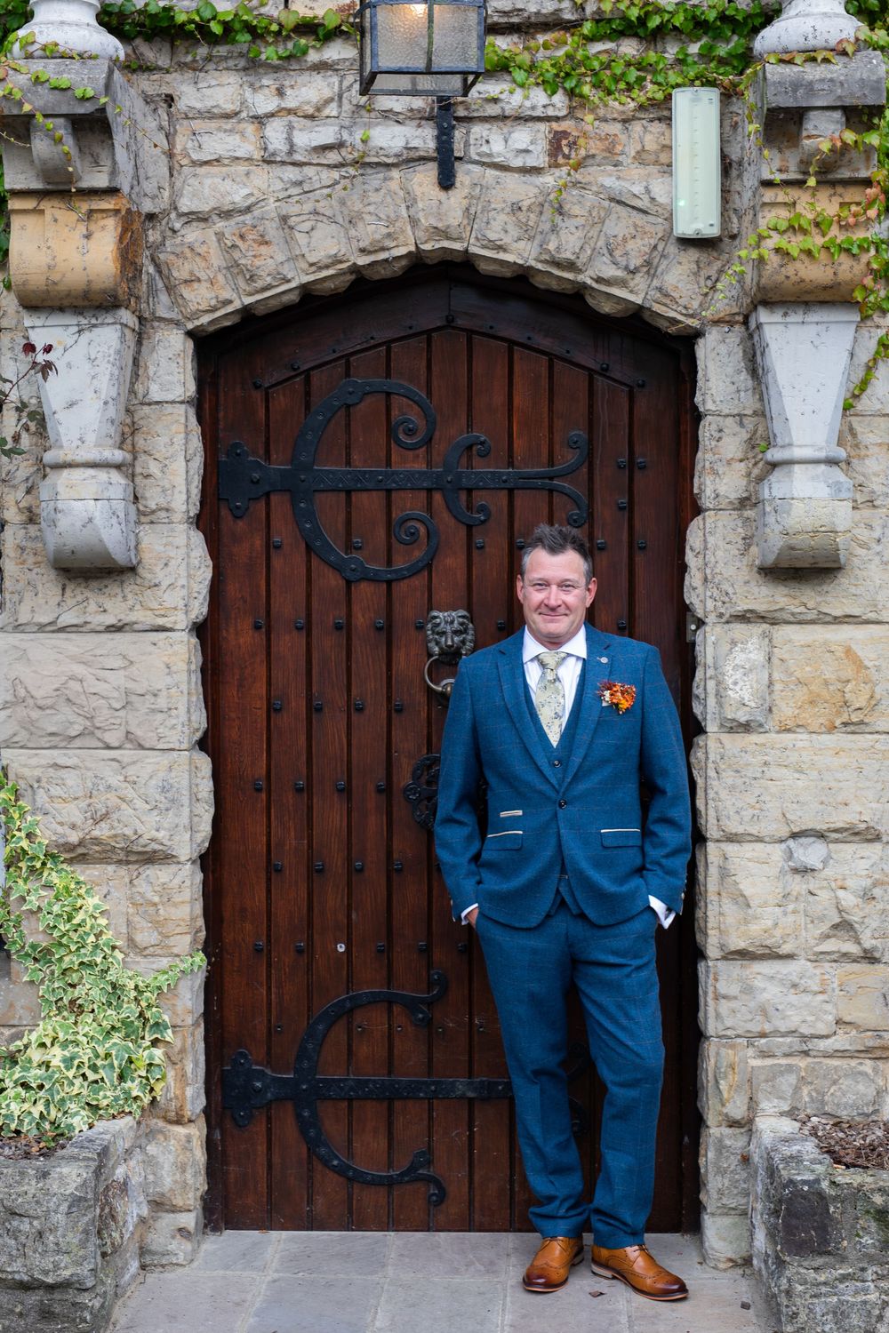 A sequence of photos showing a person in a navy blue suit posing in front of rustic stone archways and wooden doors.