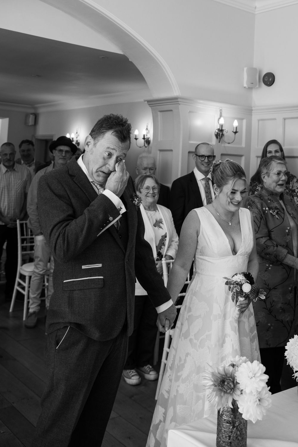 A joyful wedding ceremony moment captured in black and white as guests look on at the happy couple.
