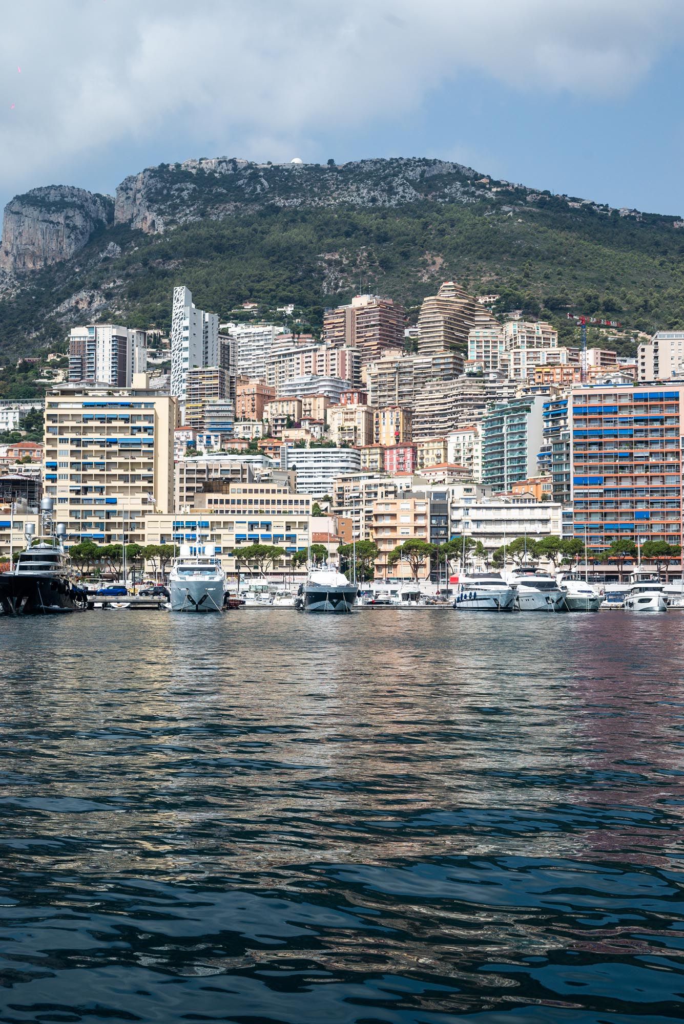 Panoramic view of Monaco's waterfront skyline with luxury yachts and modern buildings along the Mediterranean coast.