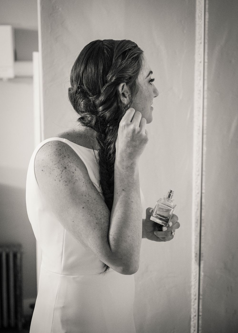 A series of black and white photos showing someone getting ready in a white dress.