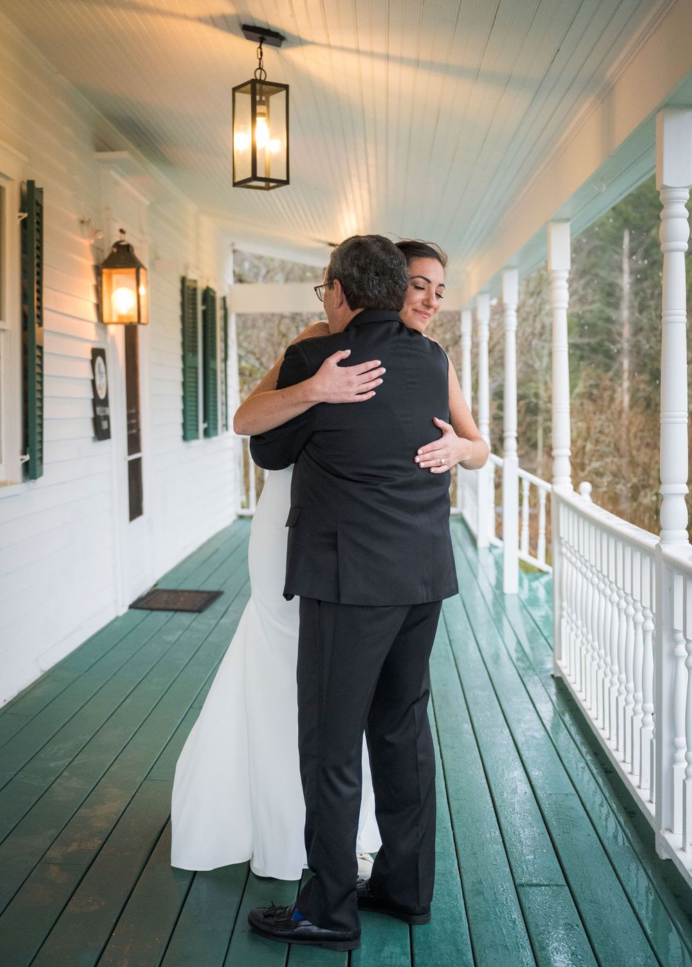 A touching first look moment captured on a white porch with green flooring and lantern lights.