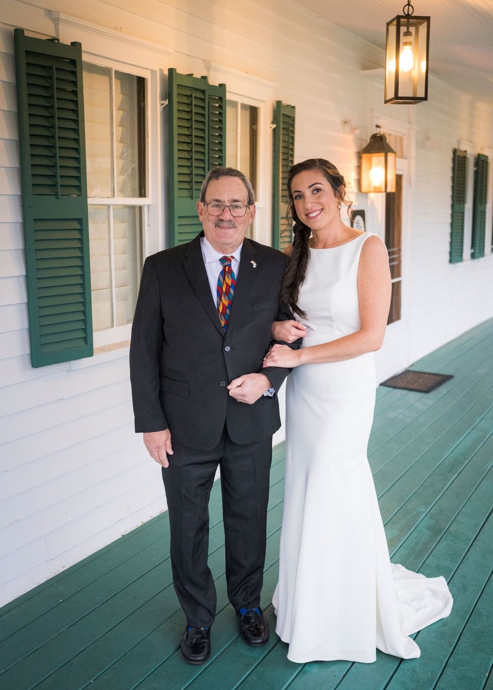 A sequence of emotional first look photos on a classic white porch with green shutters.