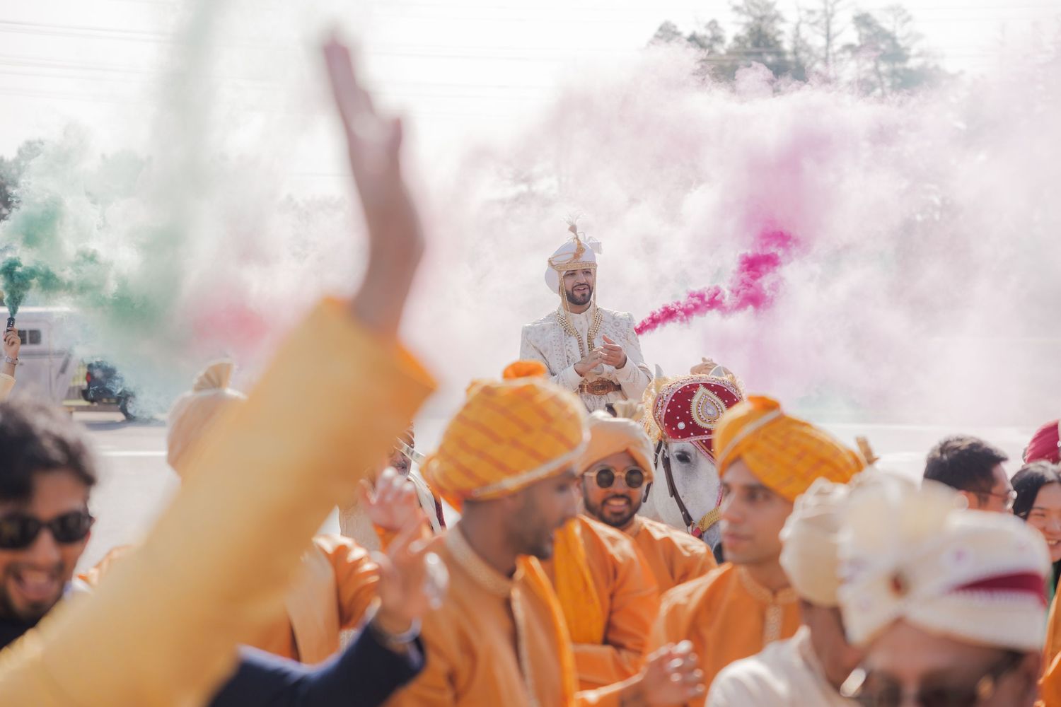 A group of people celebrate outdoors with colorful orange powder during a festival event.
