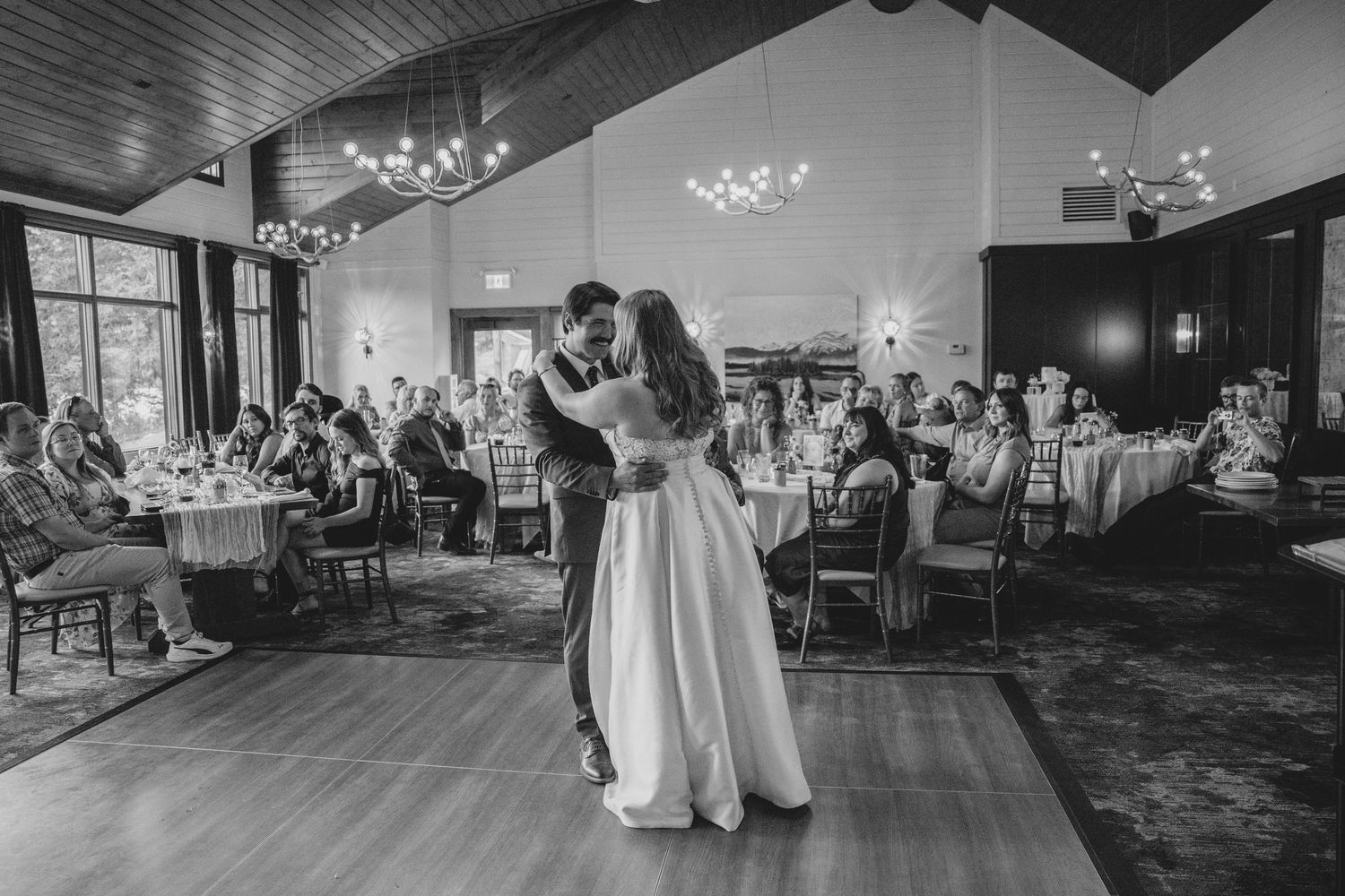Wedding reception guests dance together on a dimly lit dance floor during an evening celebration.