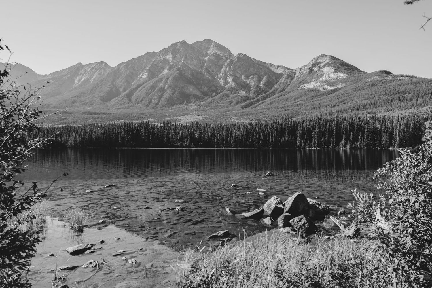 A series of black and white landscape photographs showing mountain ranges and lakes in a panoramic view.
