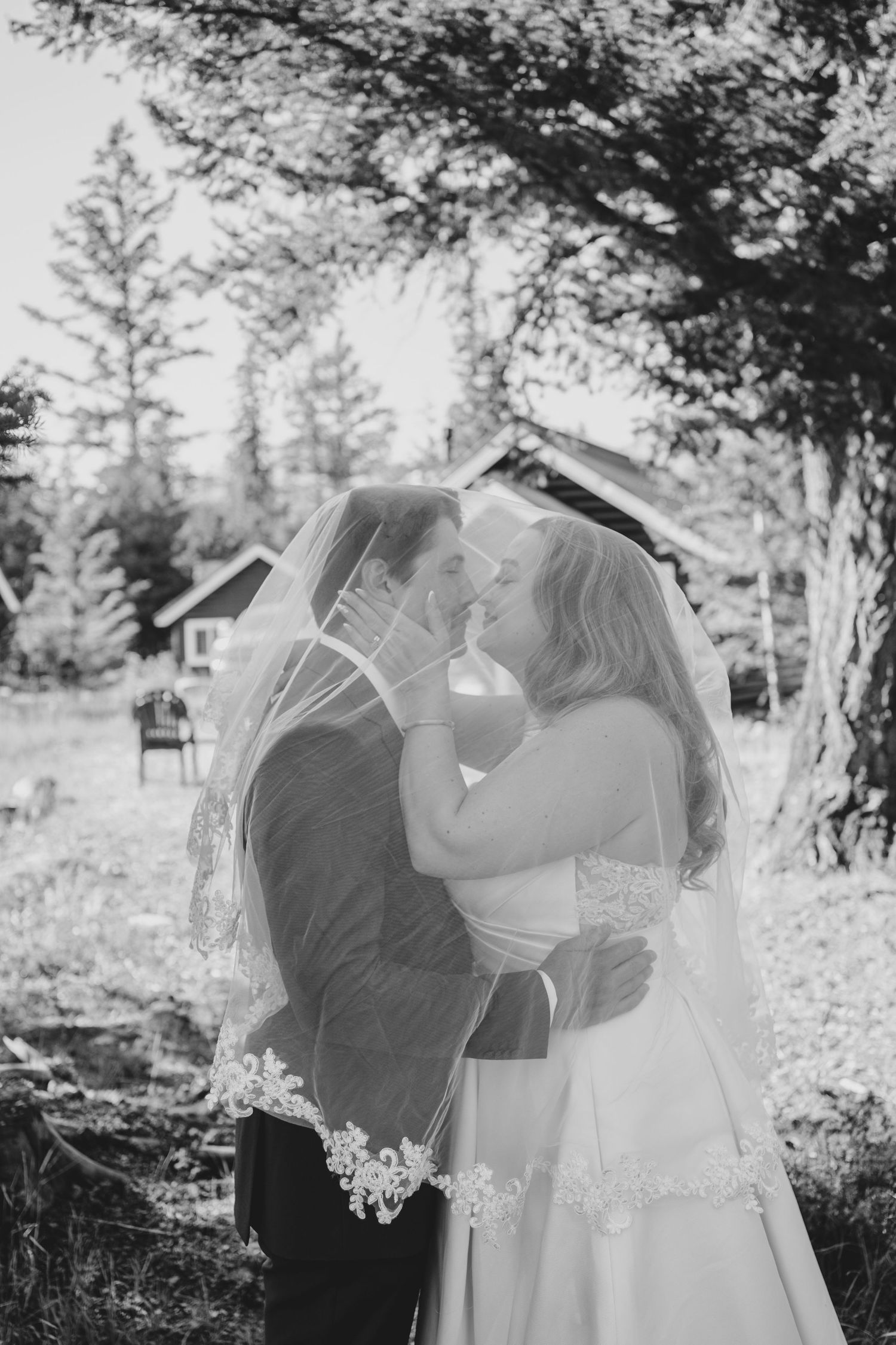 Romantic black and white wedding photos showing tender moments between a couple in an outdoor forest setting.