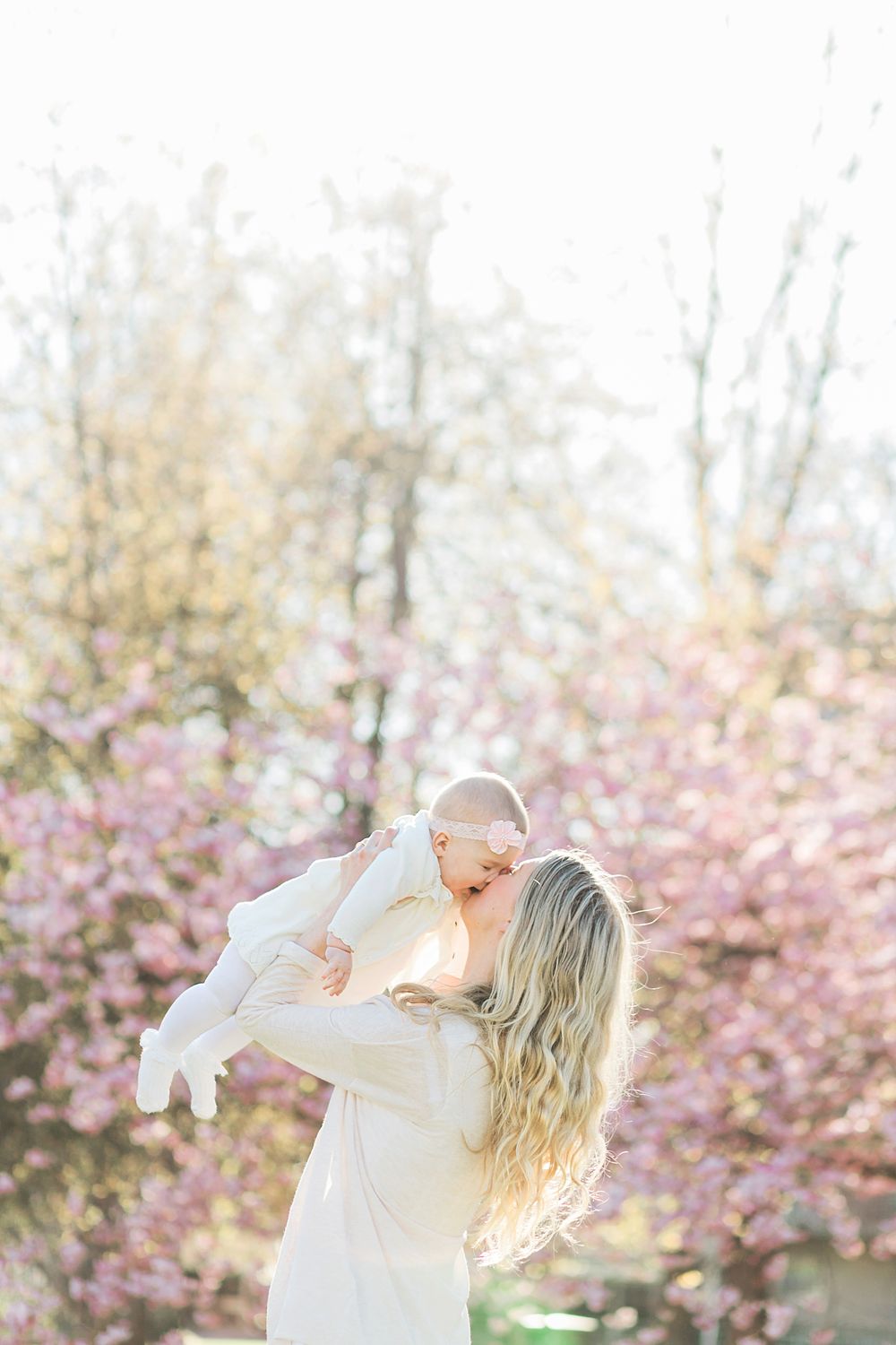 Barn- och familjefotografering i Stadsträdgården, Karlstad. Angelina lyfter upp bebis-Melissa. Solen skiner.