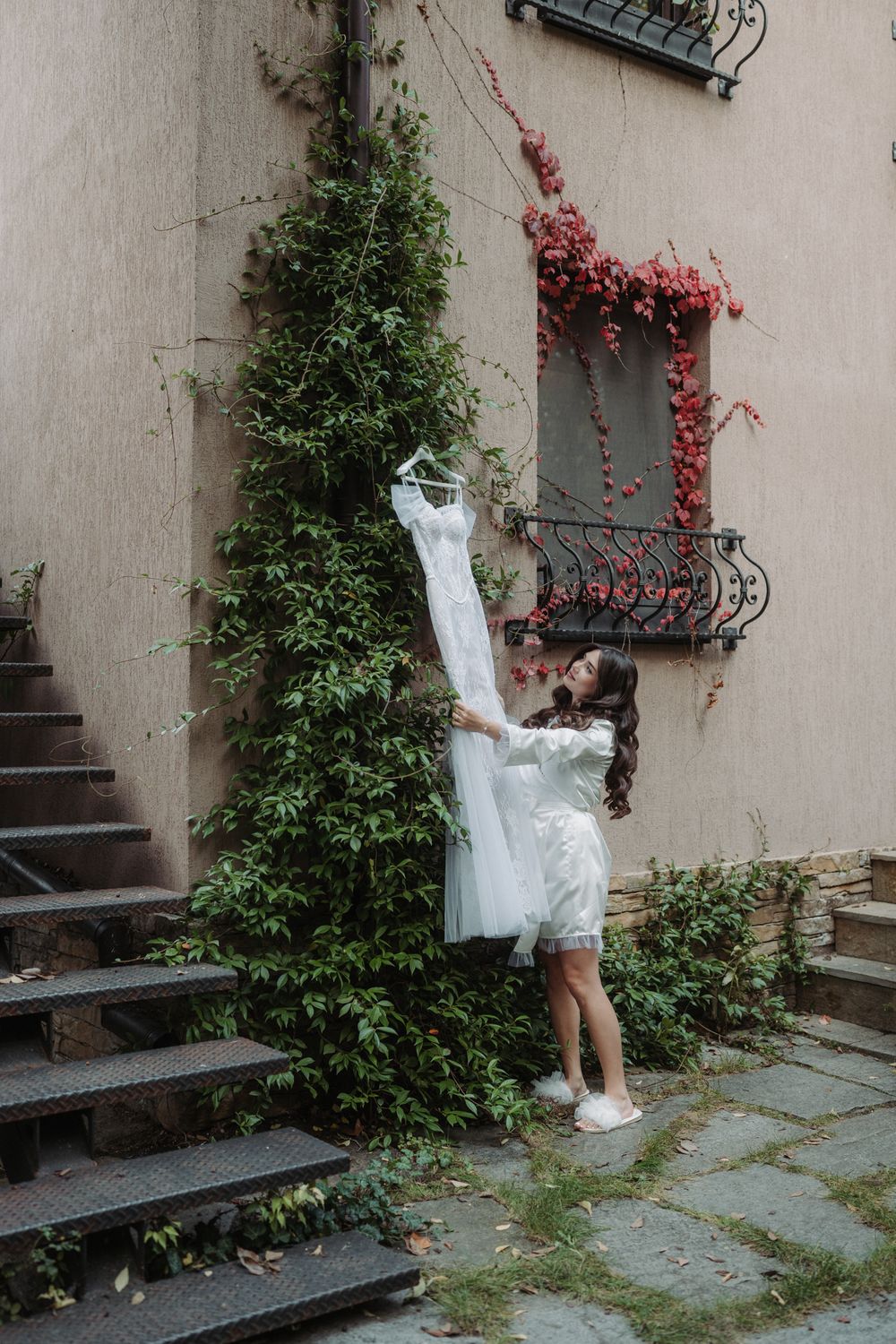 A sequence of five images showing a white dress moving through a garden space with stone steps and climbing vines.