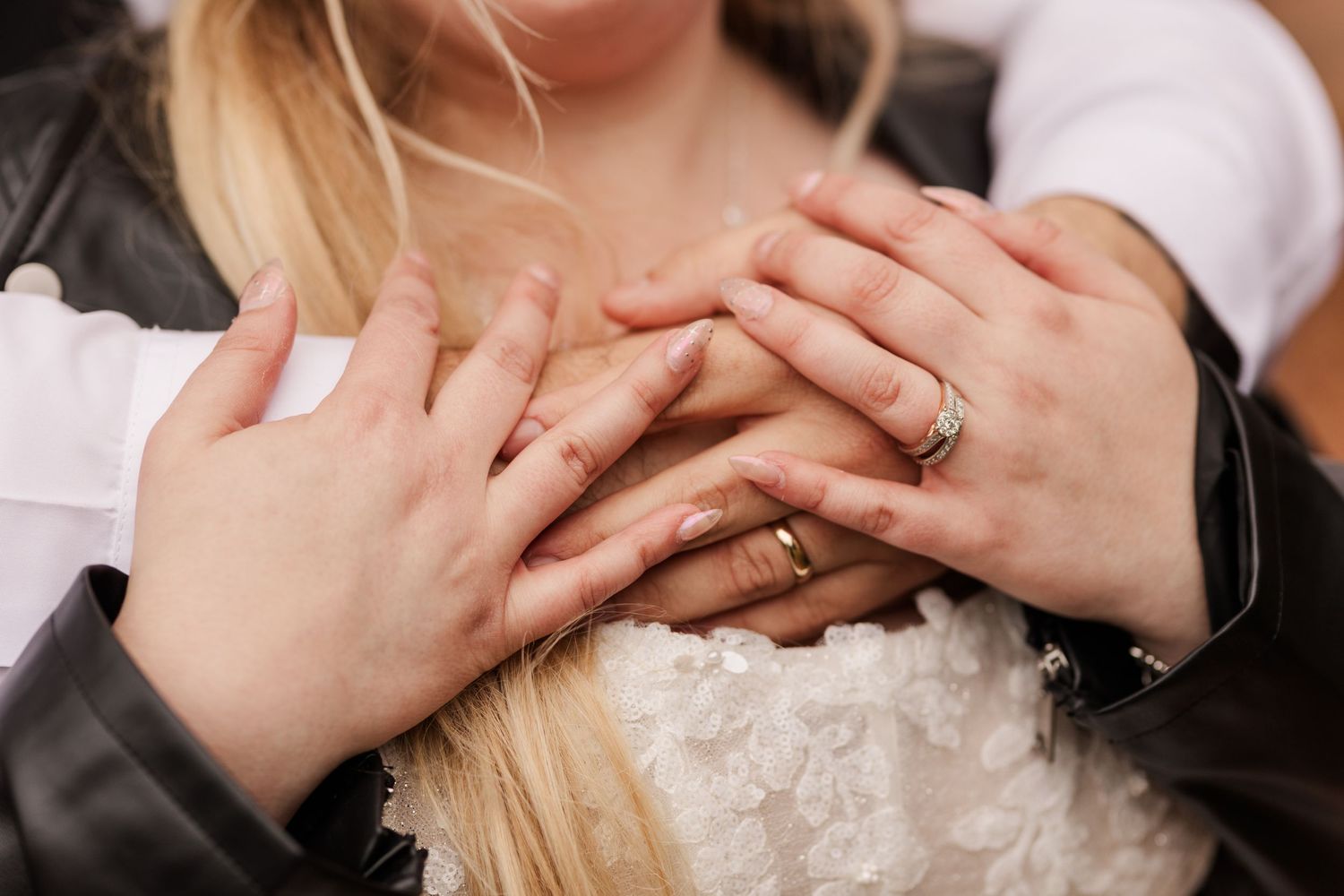 Close-up of wedding rings and hands showing intimate romantic moment against soft background.