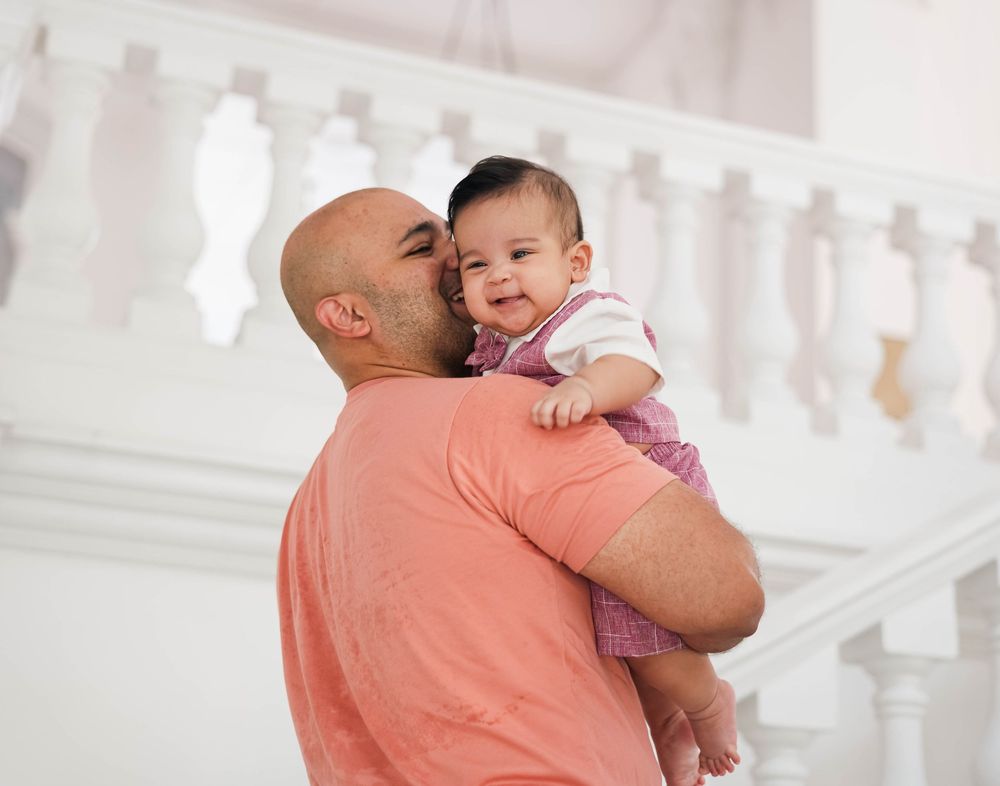 A parent in a coral shirt holds and comforts a crying baby in a series of tender moments.