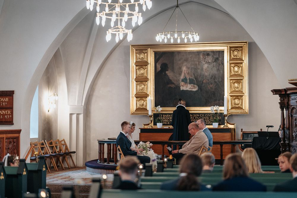 Interior view of an elegant church or concert hall with chandeliers and ornate decorative elements.