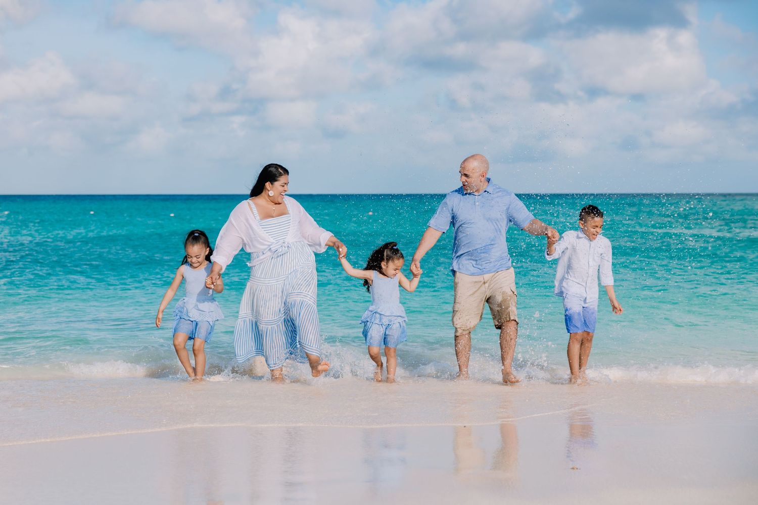 Group walking and splashing together in the shallow turquoise waters of a tropical beach.