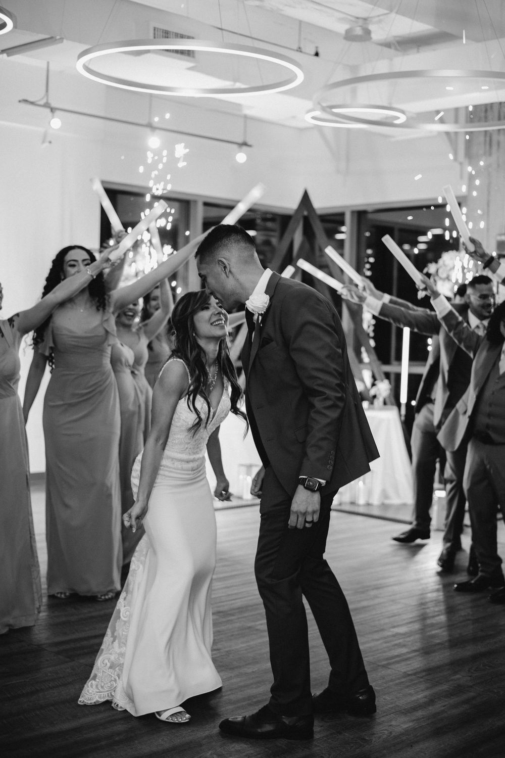 Wedding reception dance party with guests celebrating under circular lighting.