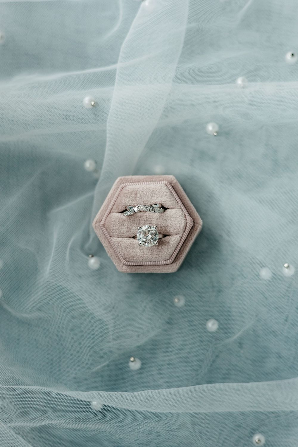 Diamond engagement ring in pink hexagonal box on delicate tulle fabric.
