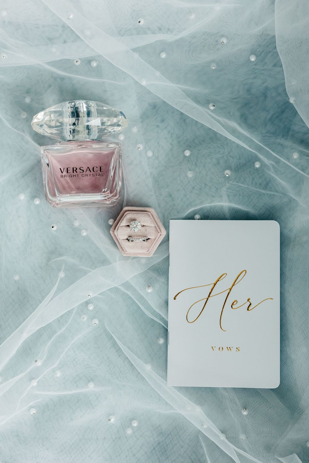 Wedding details with Versace perfume, vows card and accessories on blue fabric. Flatlay set up. Flat lay. Orlando wedding. Florida Wedding.