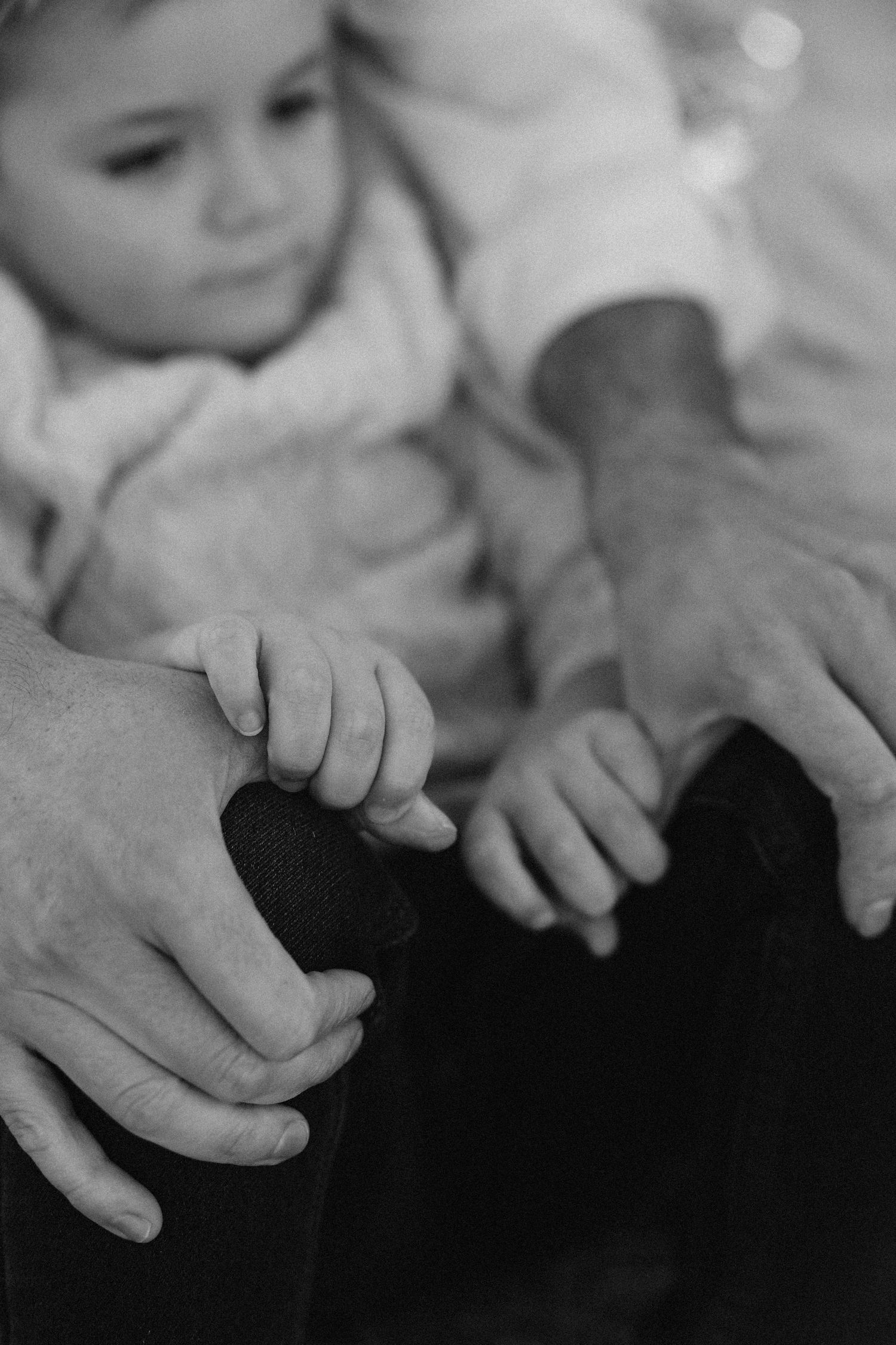 Black and white photo series showing small hands reaching and touching against a dark background.