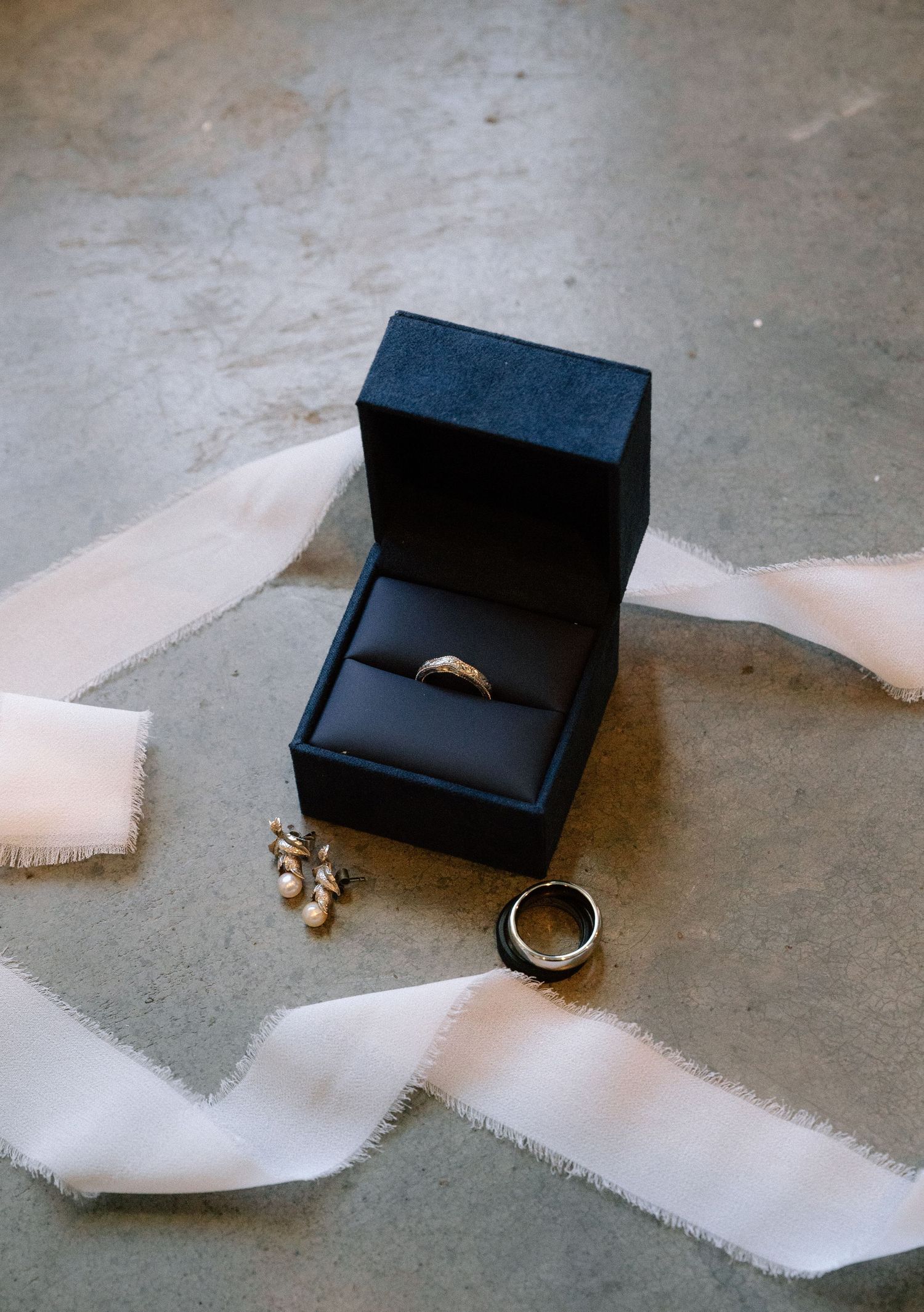 A black ring box opens progressively to reveal a gold wedding band in a sequence of four photos.
