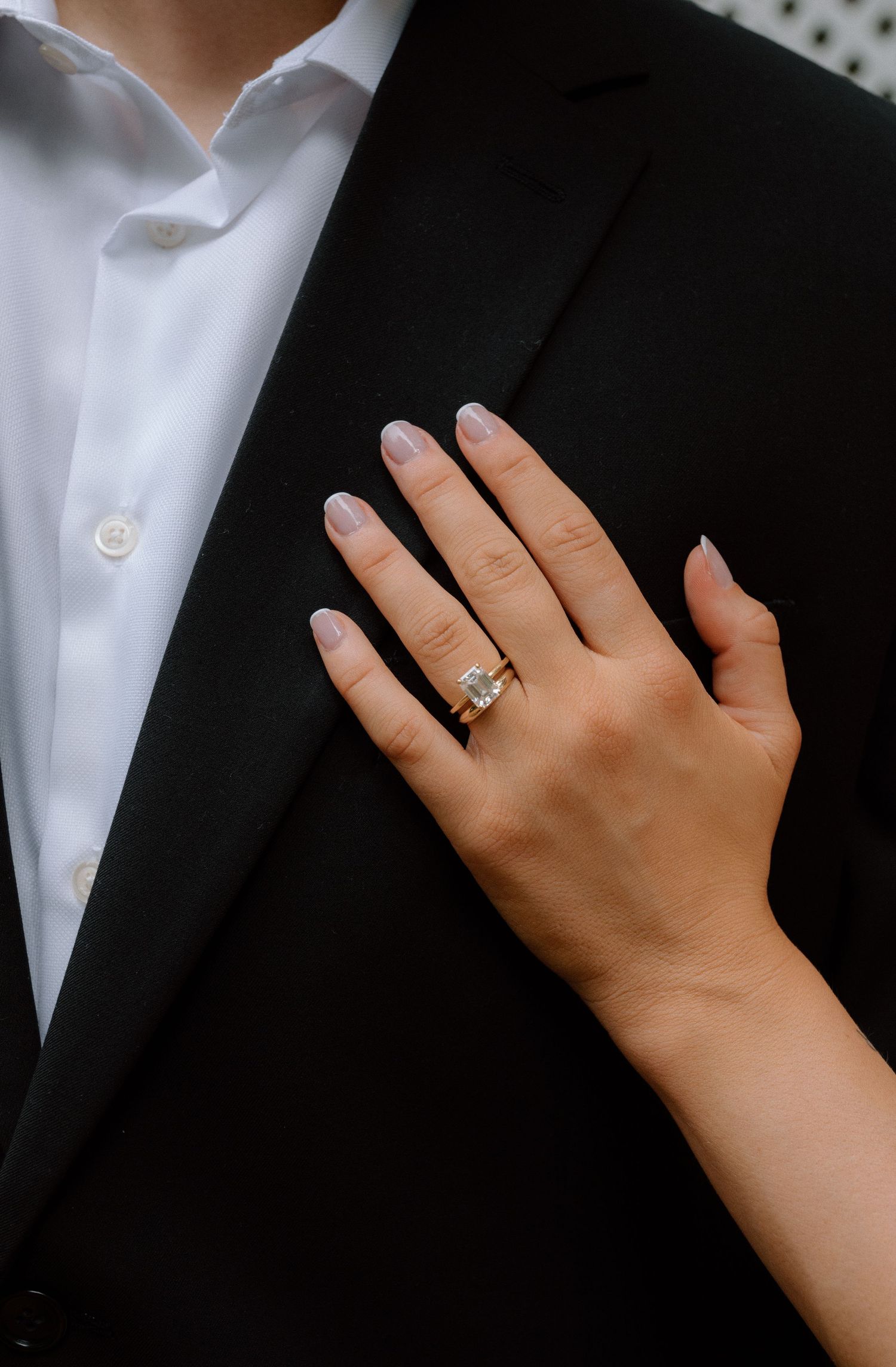 Close-up sequence showing a hand with an engagement ring resting on formal black and white wedding attire.