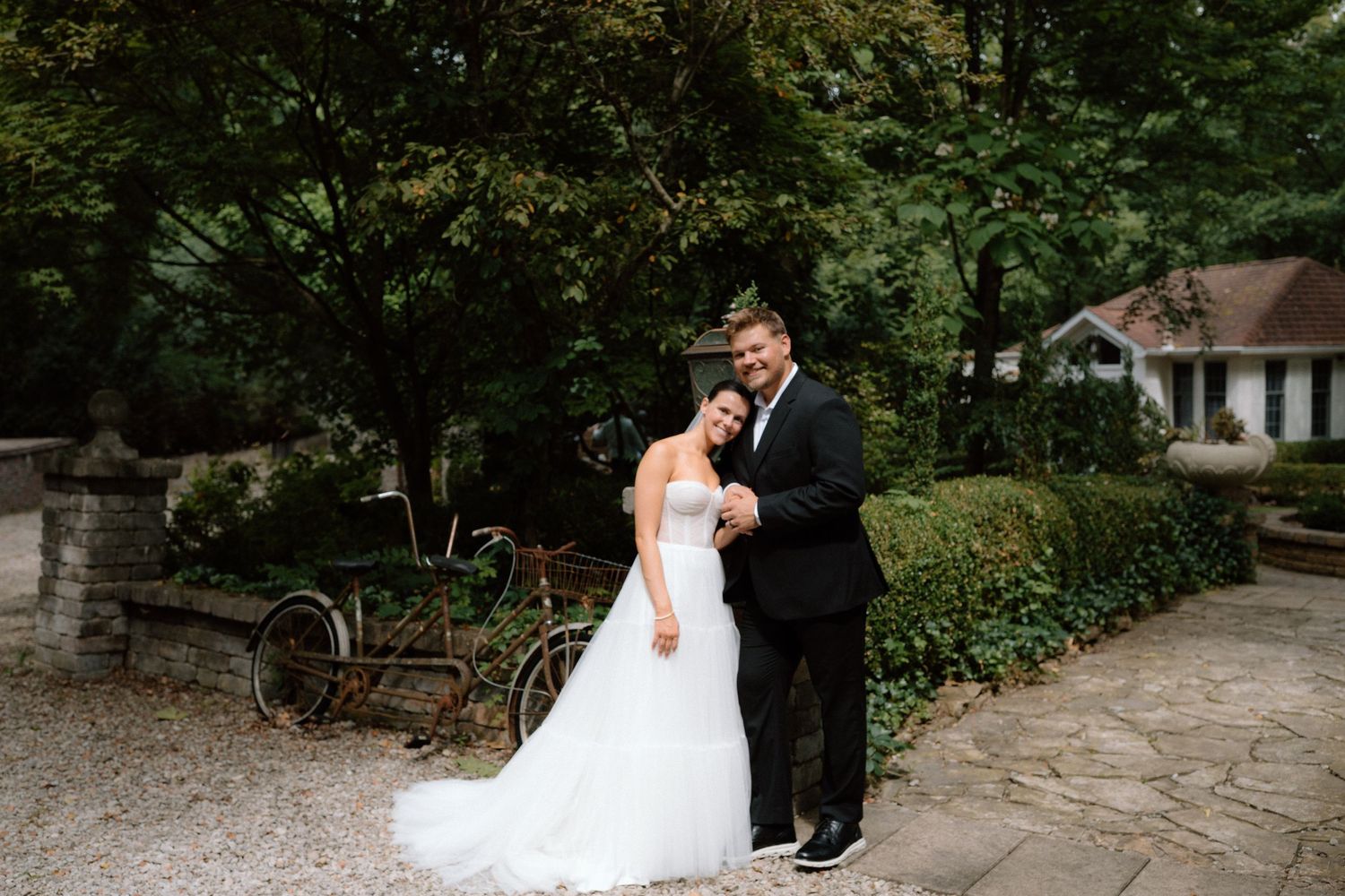 A couple in wedding attire poses together in a lush garden setting during their special day.