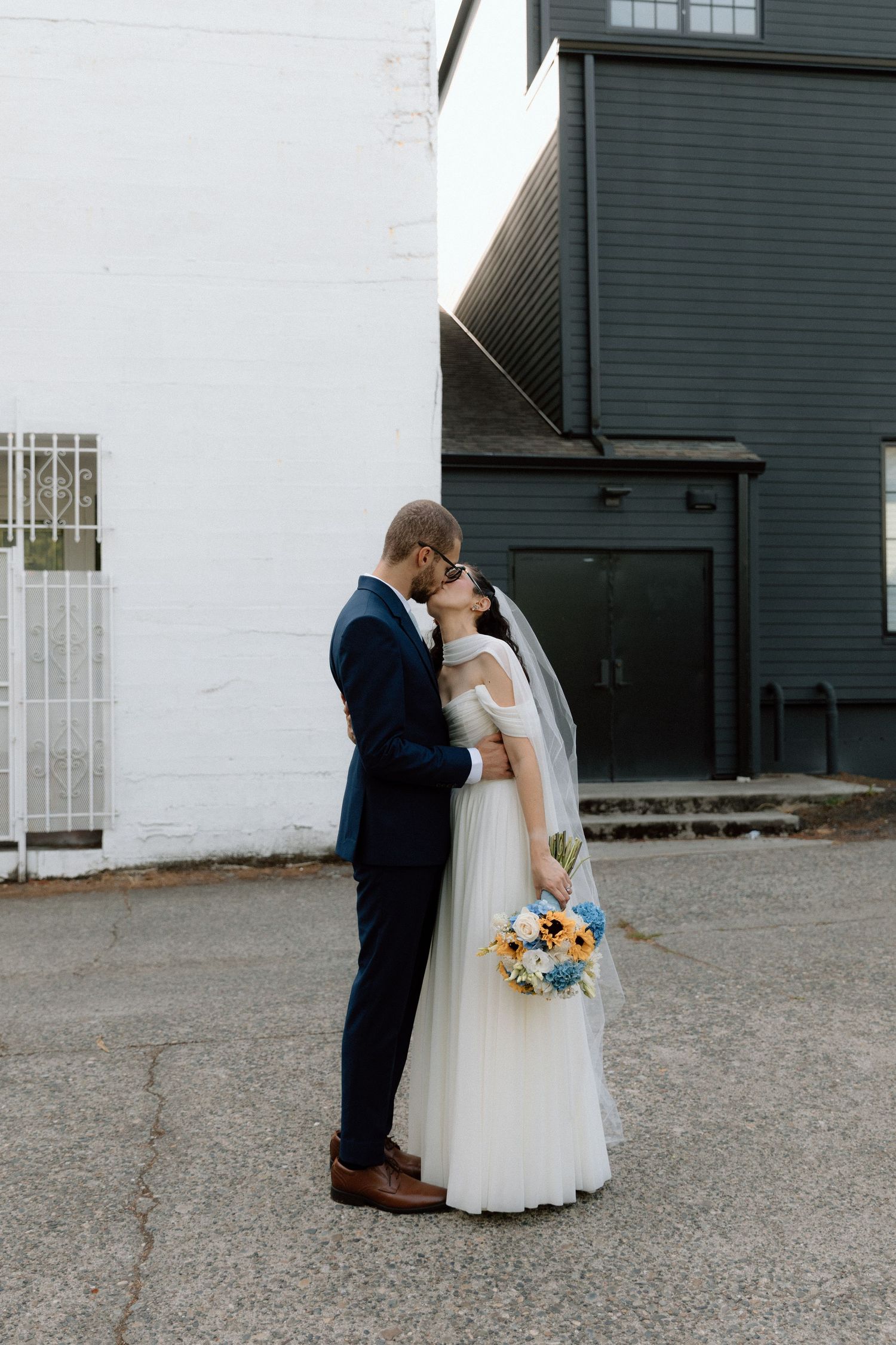 A romantic wedding couple shares intimate moments in a series of black and white photos against an industrial backdrop.