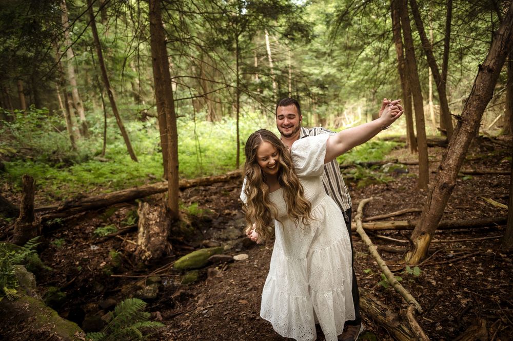 Couple poses playfully in enchanted forest setting with dramatic lighting.