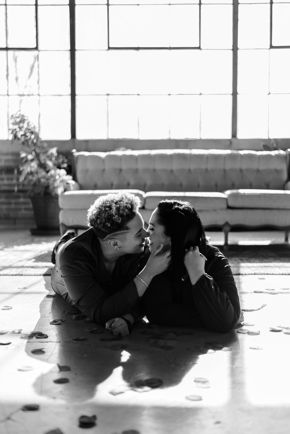 Black and white photos of a couple lying on floor near large industrial windows in Akron, Ohio.