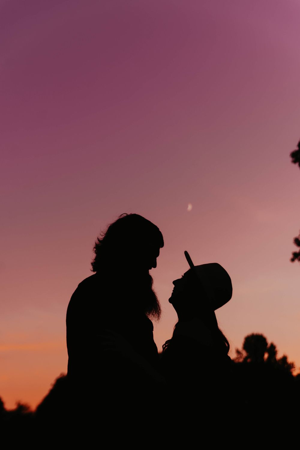 Silhouettes of figures against a purple sunset sky creating a romantic atmosphere.