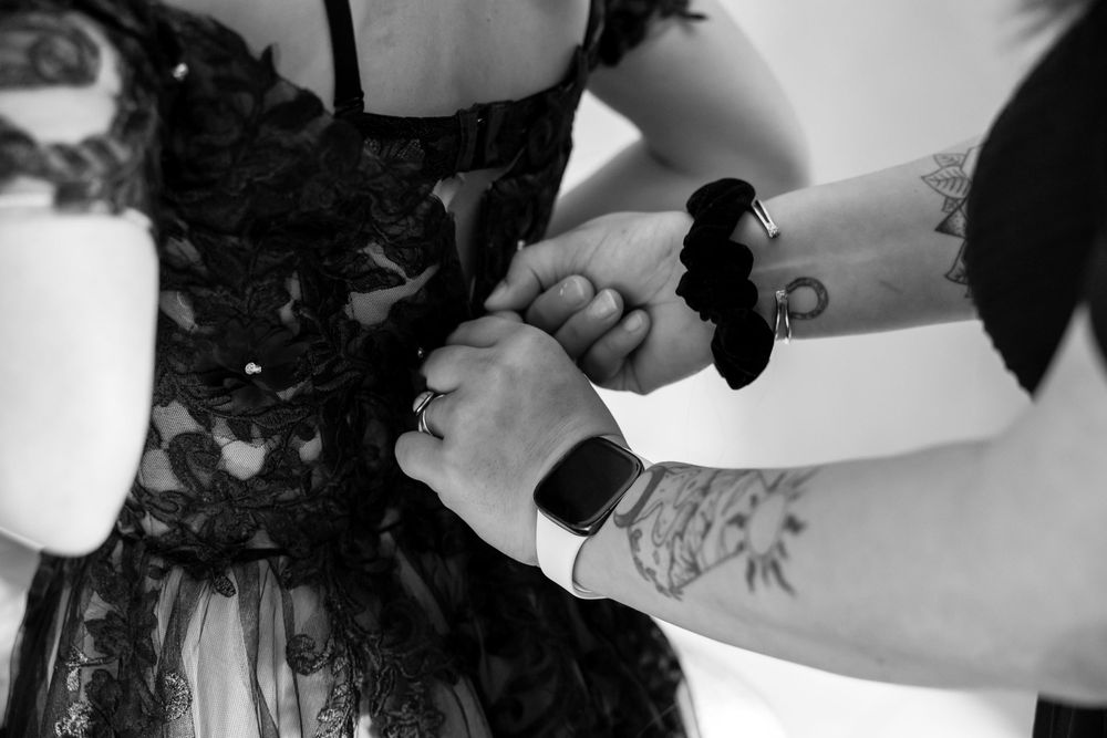 Black and white image of final wedding dress adjustments being made. Domaine des sources photographe de mariage