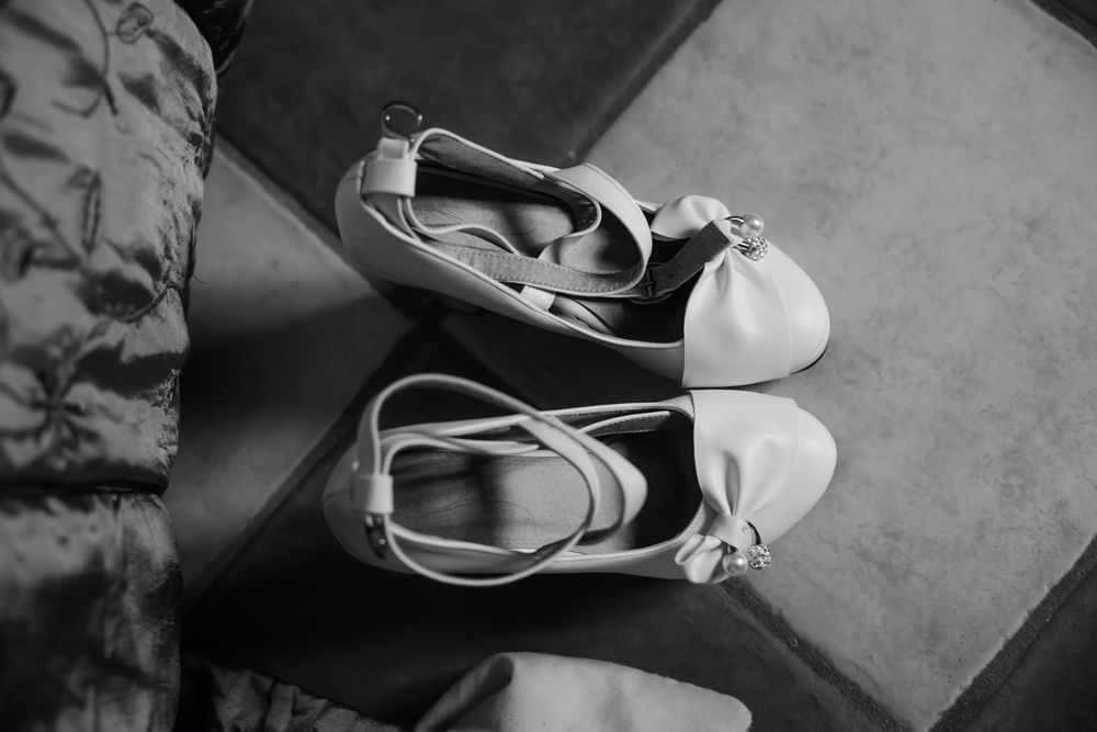 Black and white photograph of elegant bridal shoes on a textured surface. Domaine des sources photographe de mariage