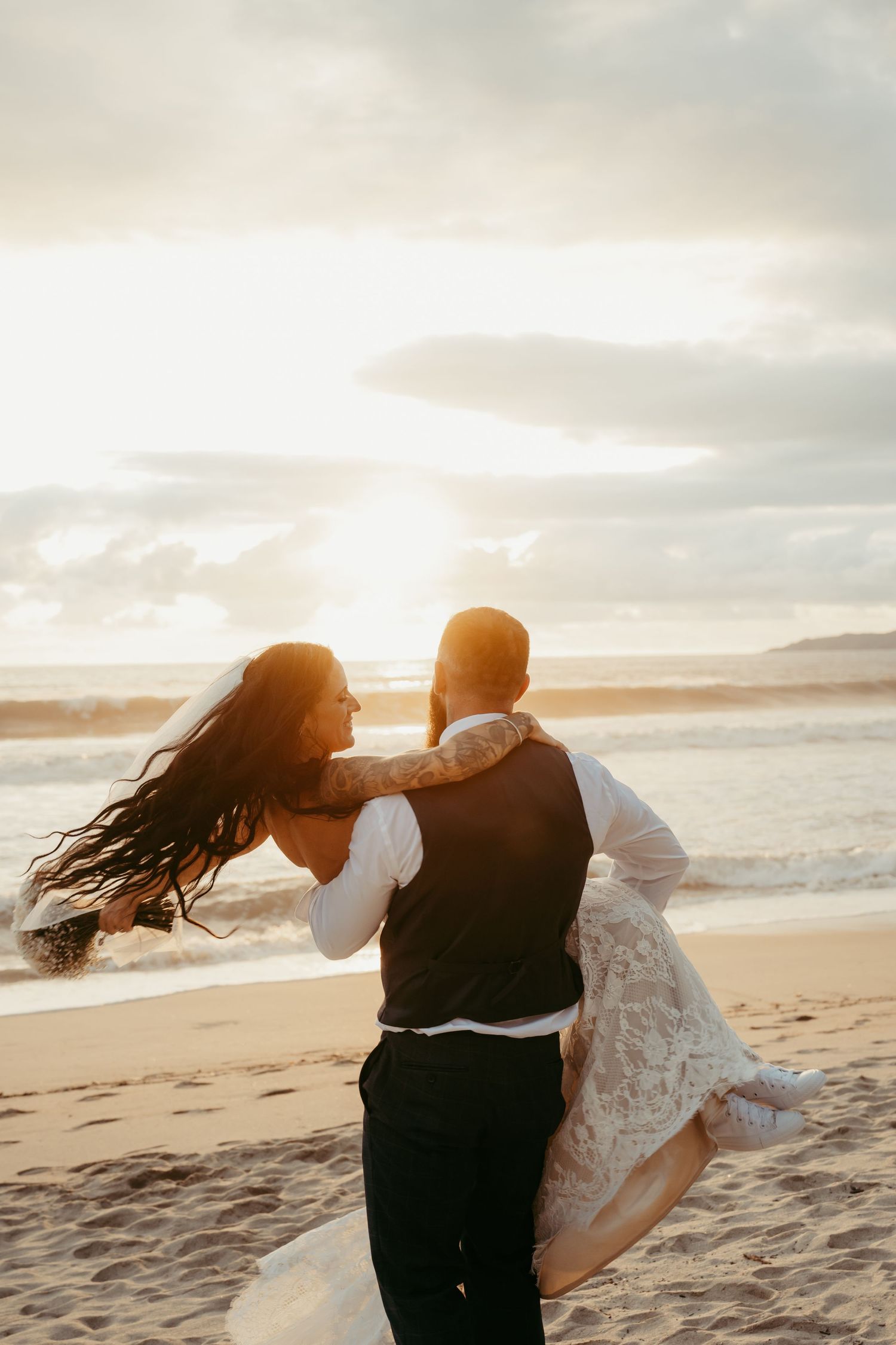 A couple dances together on a sandy beach at sunset creating a romantic silhouette against the ocean waves.