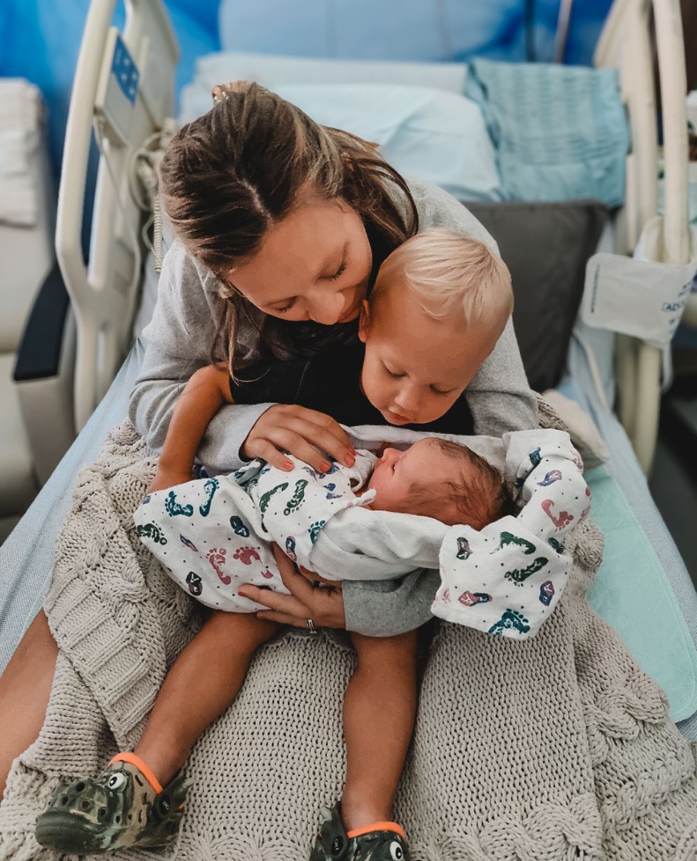 Older sibling and mom cuddling the newborn baby during fresh 48 session at hospital