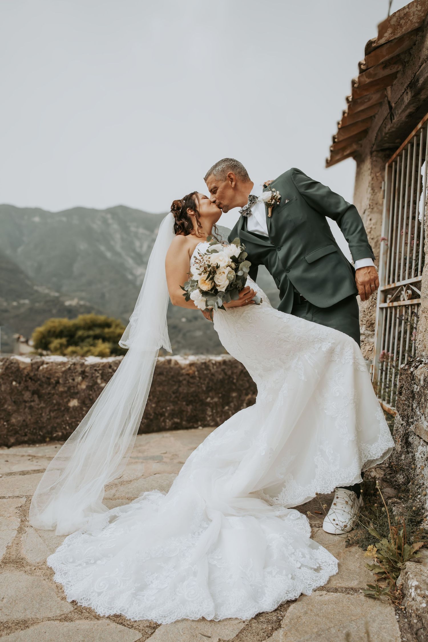 Romantic wedding couple dancing on a mountain overlook with flowing white dress.