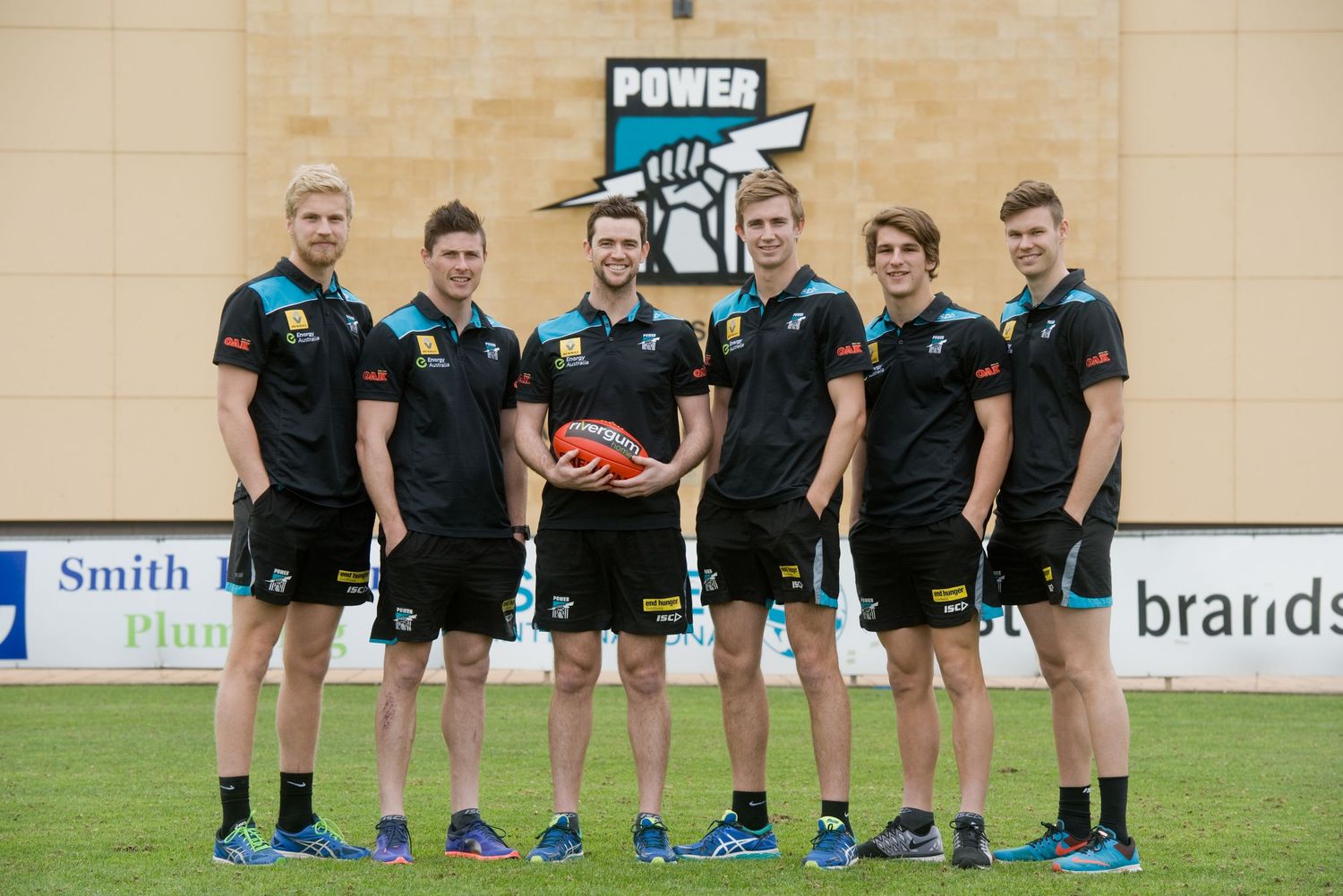 Port Adelaide Power football team players in black uniforms posing with ball.