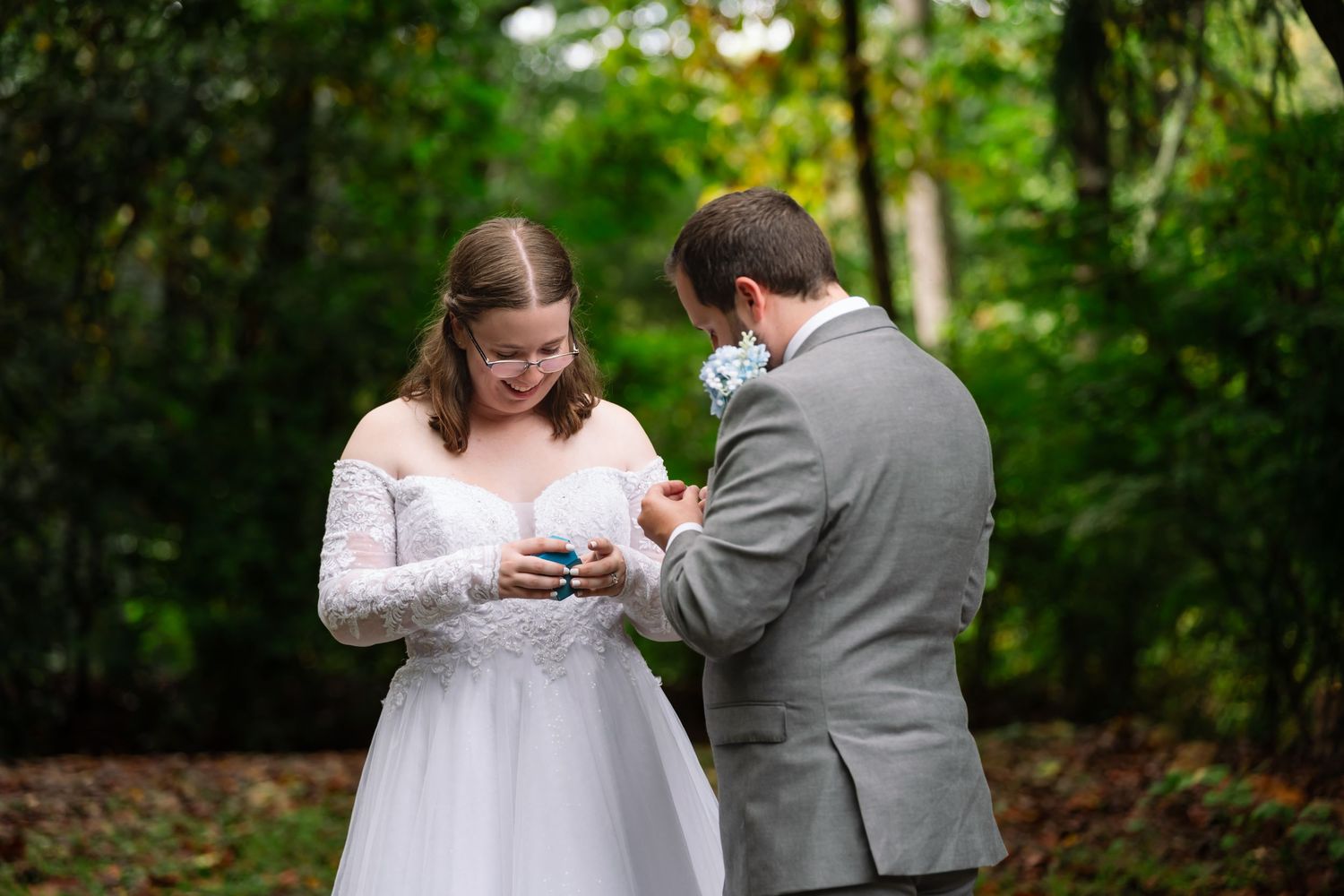 Couple in formal wedding attire sharing an intimate moment outdoors in a lush green garden setting.