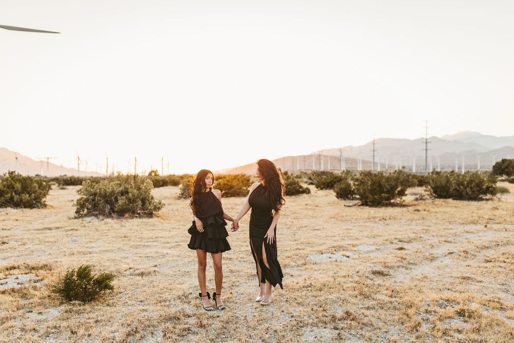 Couple and their dog walking together in a desert landscape at sunset with mountains in the distance.
