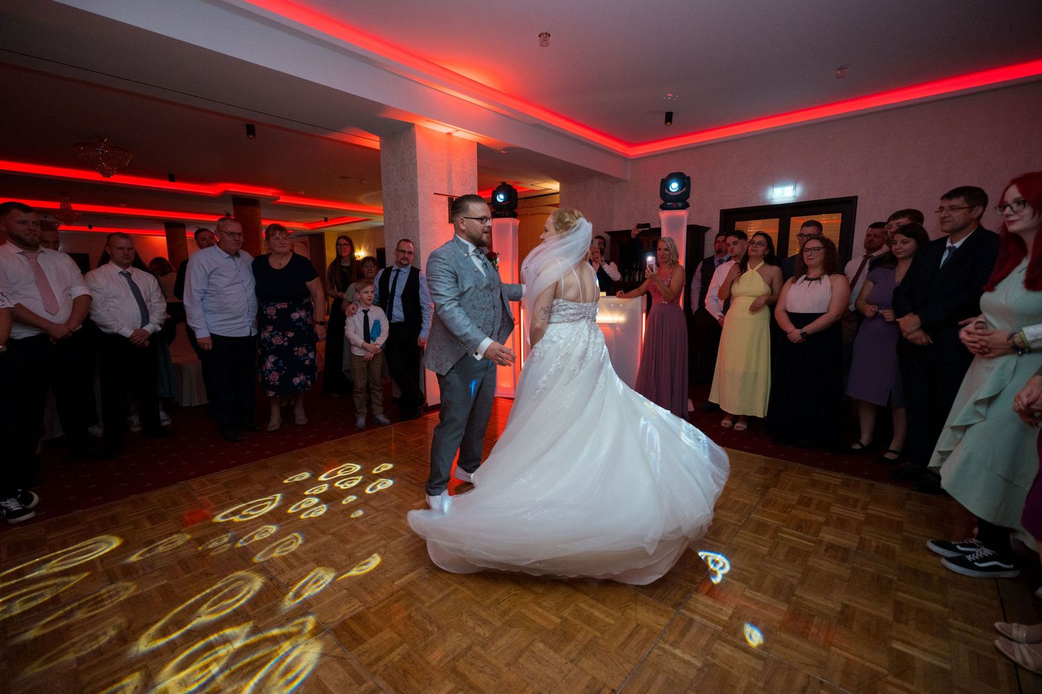 Erster Tanz des Brautpaars im Festsaal des Lakeside Burghotel Strausberg mit rotem Teppich und festlicher Beleuchtung – Hochzeitsfotograf St