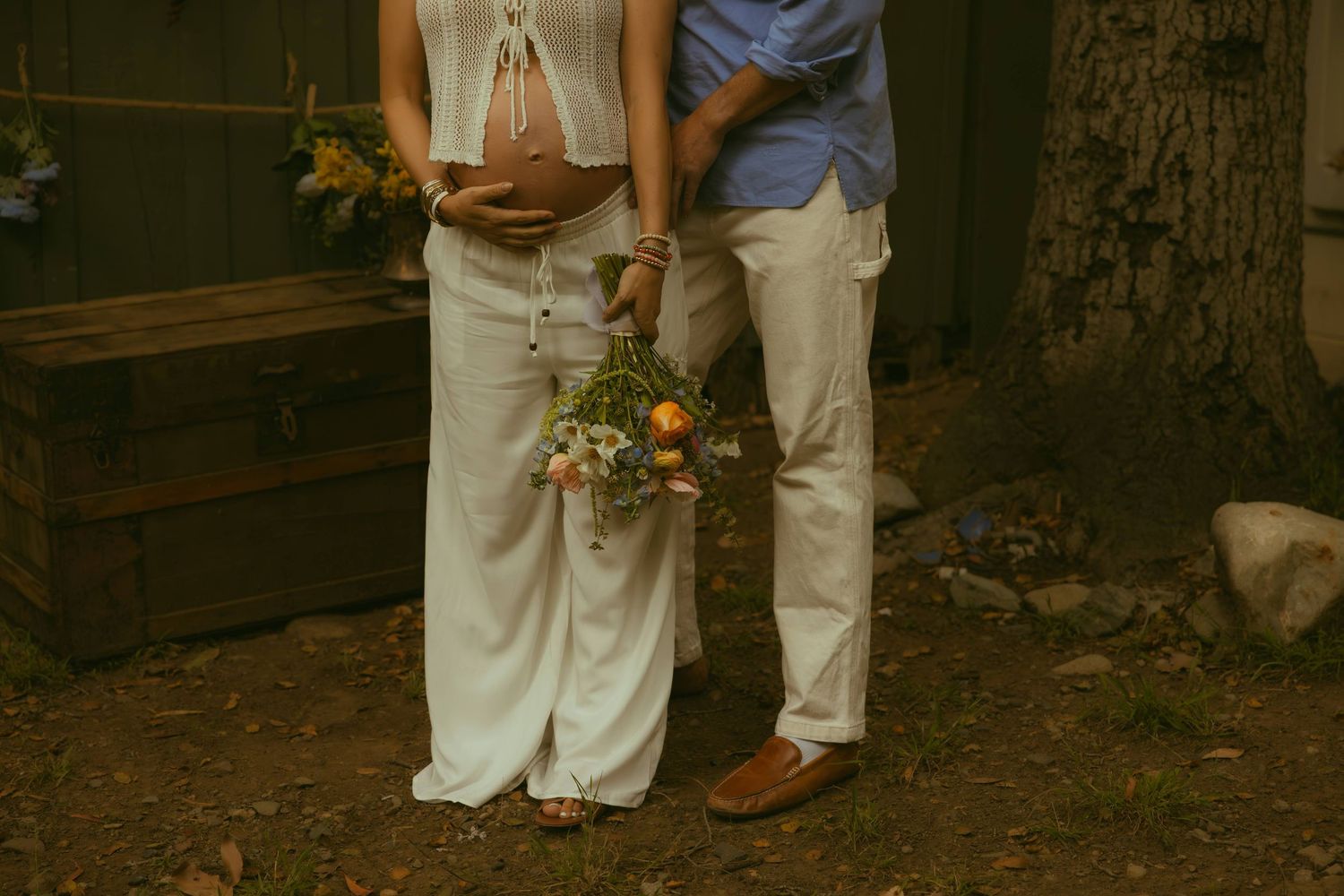 Couple in white outfits holding a wildflower bouquet with orange and white blooms, captured by a Los Angeles family photographer.
