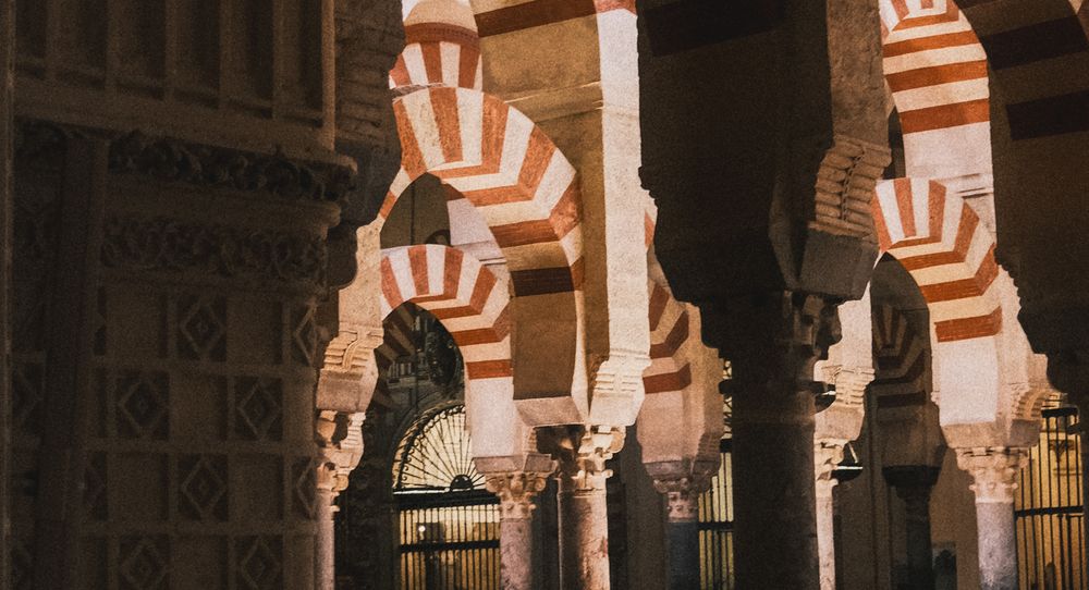 Interior of Mezquita-Catedral de Córdoba featuring iconic red and white striped arches and ornate columns.
