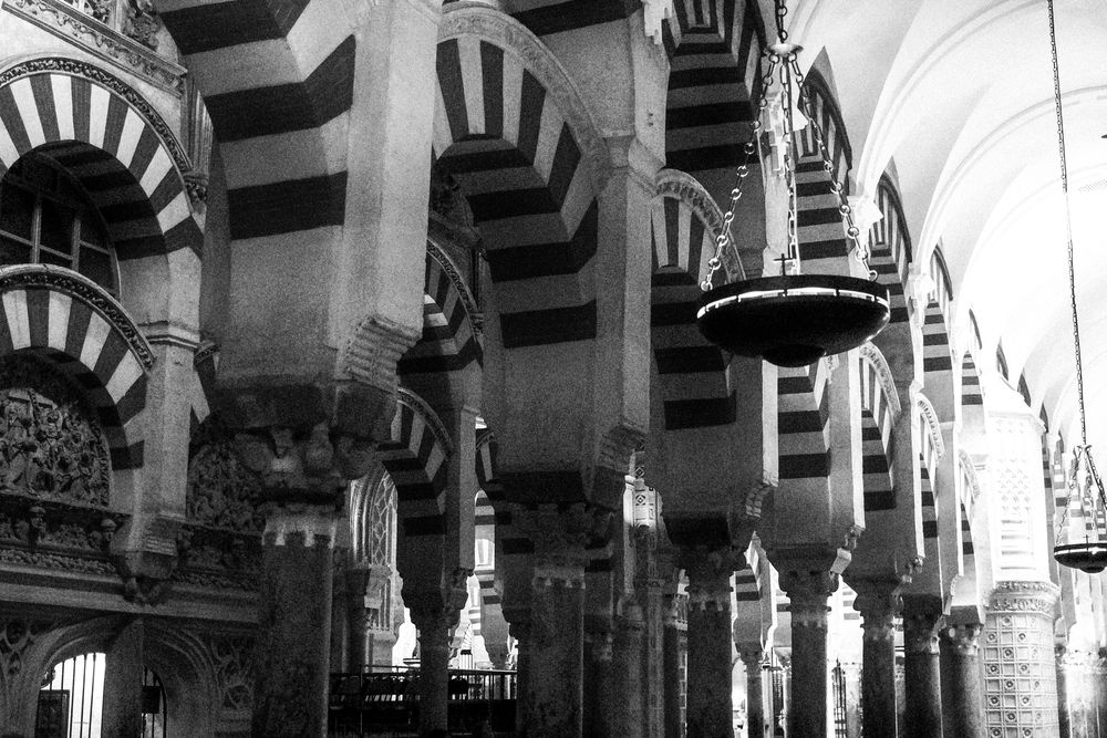 Interior of Mezquita-Catedral de Córdoba featuring iconic red and white striped arches and ornate columns.