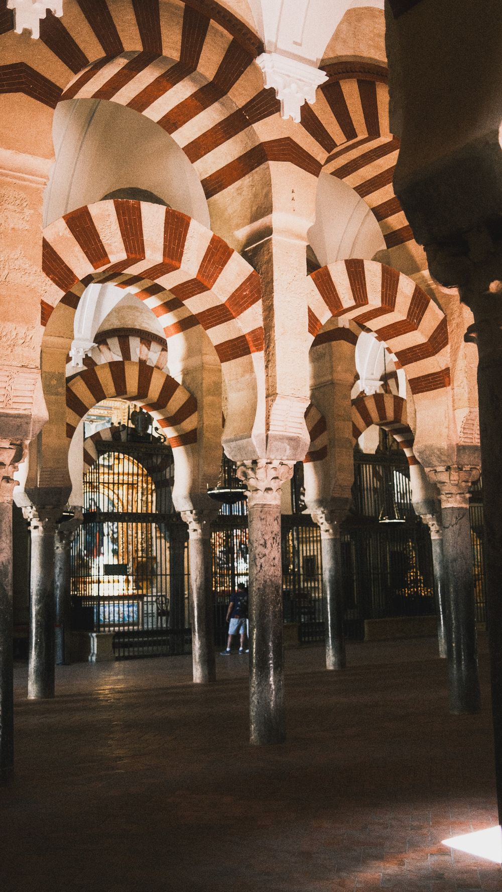 Interior of Mezquita-Catedral de Córdoba featuring iconic red and white striped arches and ornate columns.