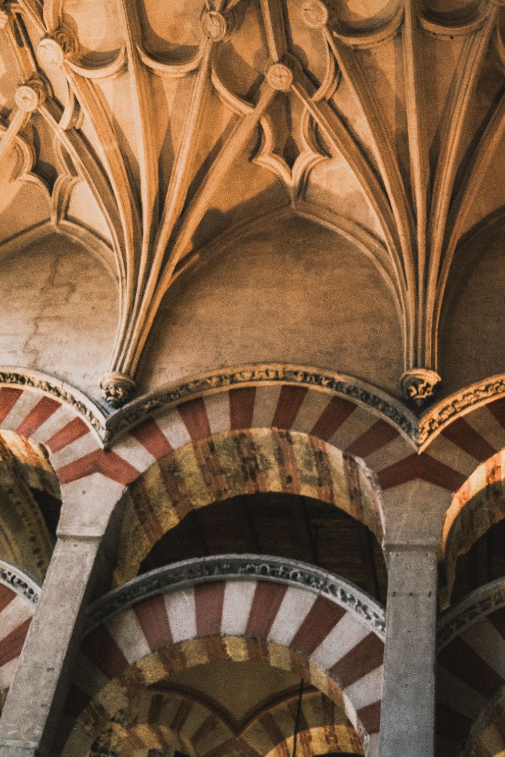 Interior of Mezquita-Catedral de Córdoba featuring iconic red and white striped arches and ornate columns.