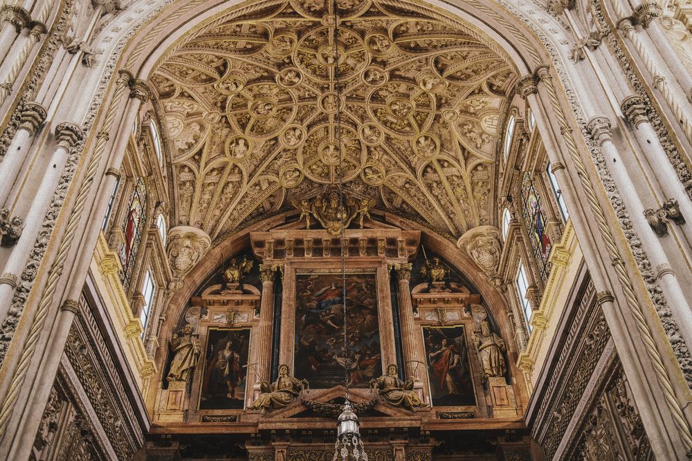 Interior of Mezquita-Catedral de Córdoba featuring iconic red and white striped arches and ornate columns.